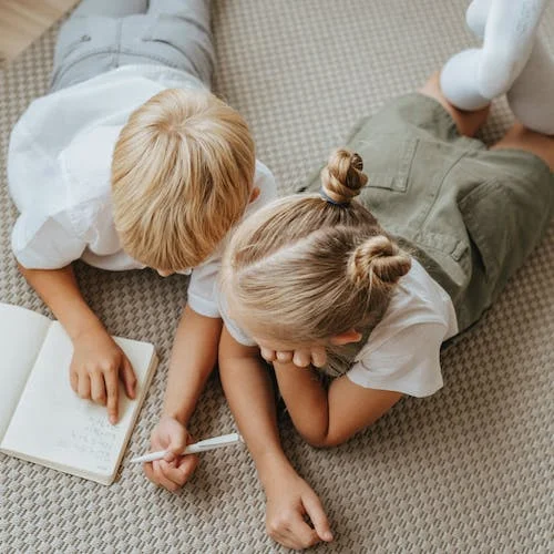 Kids laying on carpet reading from a book